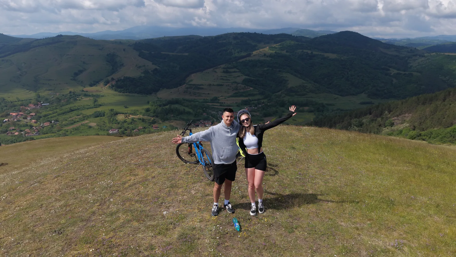 Cuplu pe culme cu bicicleta, panoramă peste Apuseni