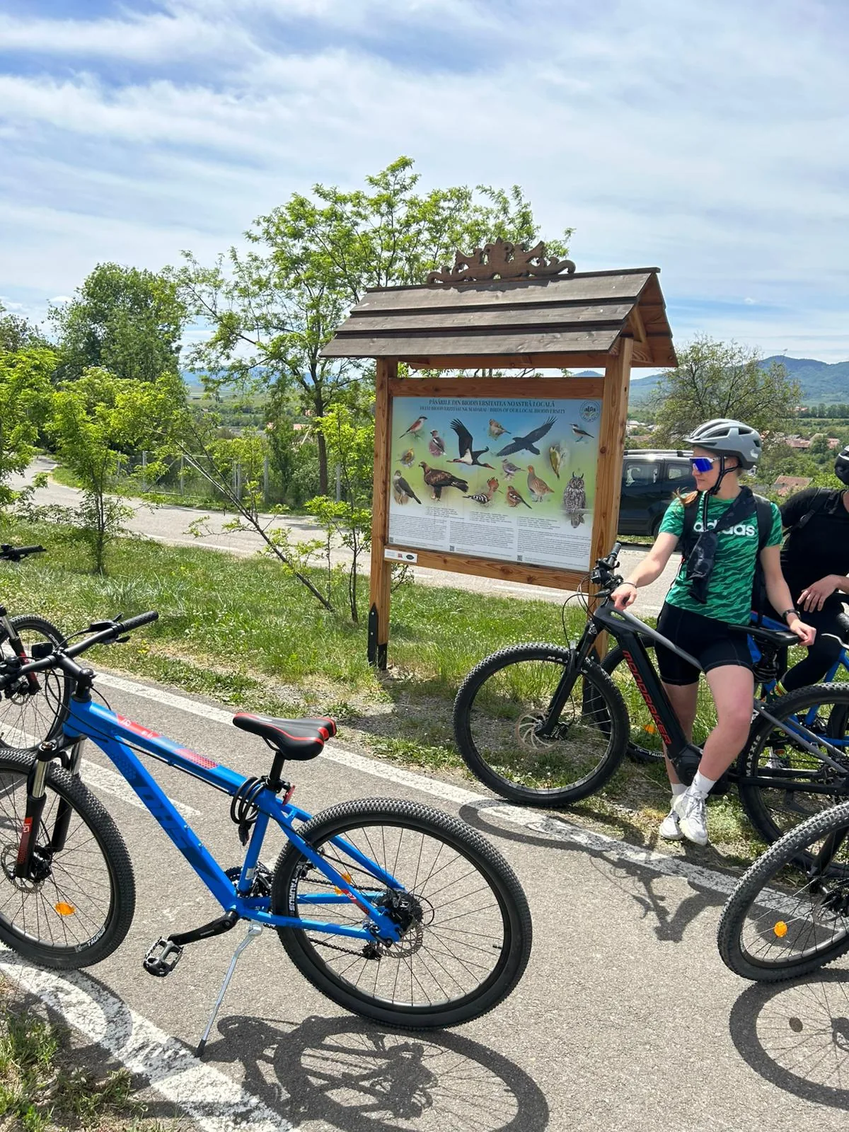 Grup de cicliști lângă un panou de biodiversitate